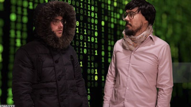 Pilgrims: Dr Kyle and Jake in front of a wall of green code